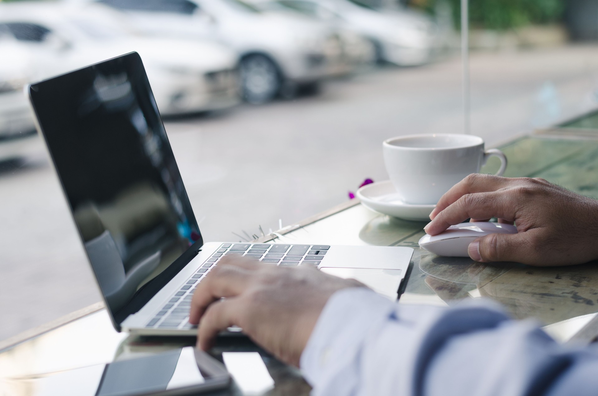 vêtements de travail homme ou freelance travaillant sur ordinateur portable, clavier et tenant dans la tasse de café sur la table à café.